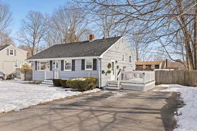 view of front of property with driveway, roof with shingles, fence, and a wooden deck