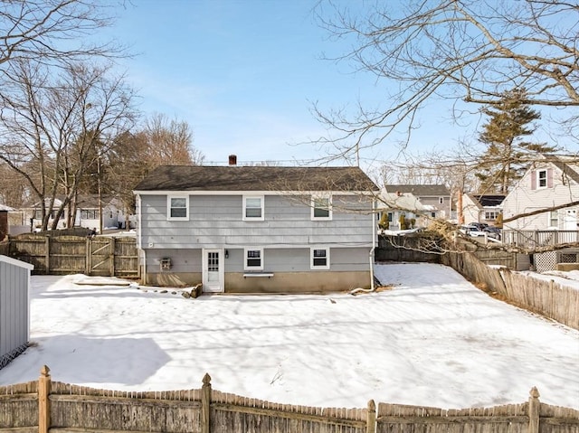 snow covered house featuring a fenced backyard and a residential view