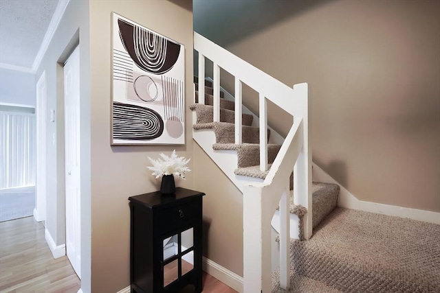 staircase with hardwood / wood-style floors and ornamental molding