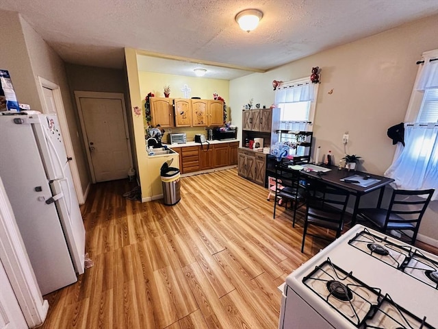 32 Ames St, Worcester, MA 01604 - kitchen with white appliances, light wood finished floors, a textured ceiling, light countertops, and brown cabinets