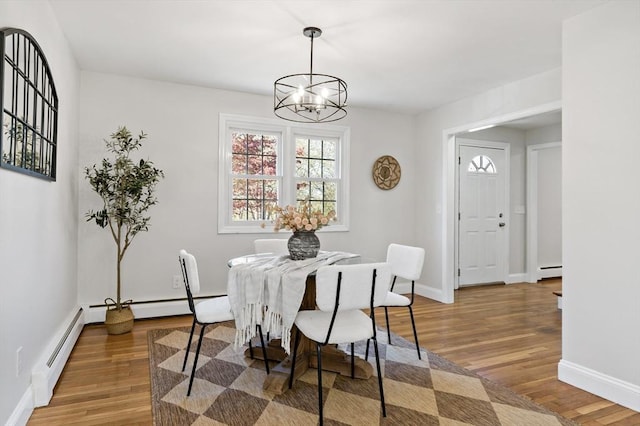 dining room featuring an inviting chandelier, a baseboard radiator, and wood finished floors