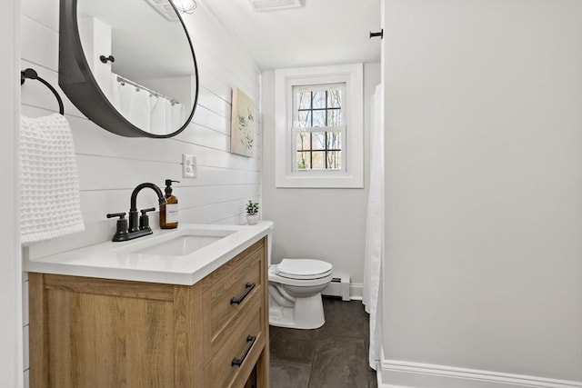full bathroom with vanity, baseboards, baseboard heating, and toilet