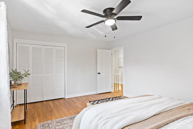 bedroom with baseboards, ceiling fan, wood finished floors, and a closet