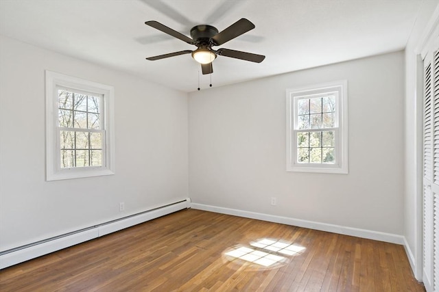 spare room featuring baseboards, plenty of natural light, baseboard heating, and hardwood / wood-style floors
