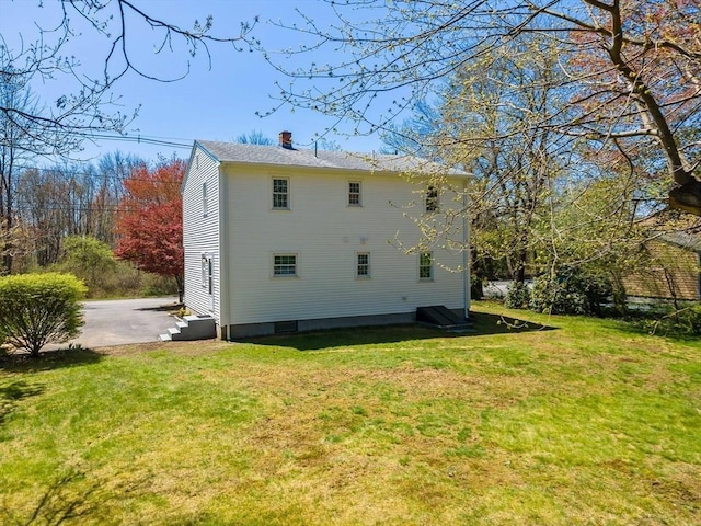 rear view of house featuring a yard and a chimney