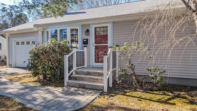 doorway to property featuring a shingled roof and a garage