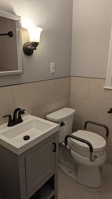 bathroom with tile patterned floors, toilet, tile walls, and vanity