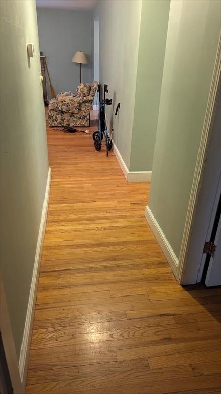 corridor featuring light wood-style flooring and baseboards