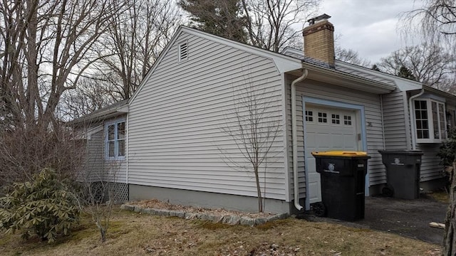 view of side of property featuring a chimney and a garage