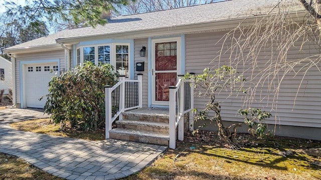 doorway to property with an attached garage and a shingled roof