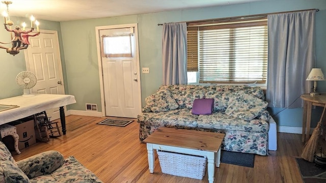 living room featuring visible vents, baseboards, an inviting chandelier, and wood finished floors