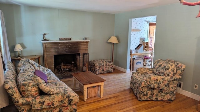 living room featuring visible vents, baseboards, wood finished floors, and a fireplace