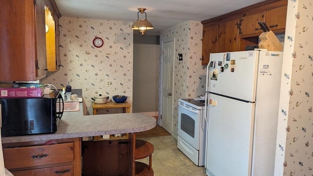 kitchen with brown cabinets, wallpapered walls, white appliances, a peninsula, and light countertops