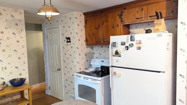 kitchen with wallpapered walls, white appliances, brown cabinets, and pendant lighting