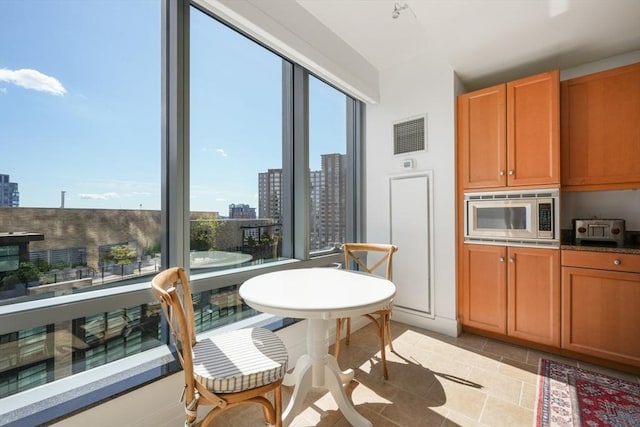 kitchen featuring stainless steel microwave, a city view, visible vents, and plenty of natural light