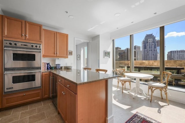kitchen featuring tile patterned floors, stainless steel double oven, light stone countertops, a peninsula, and a view of city