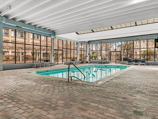 pool featuring a patio area, glass enclosure, and fence