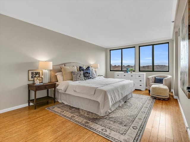 bedroom featuring baseboards, multiple windows, and light wood-style floors