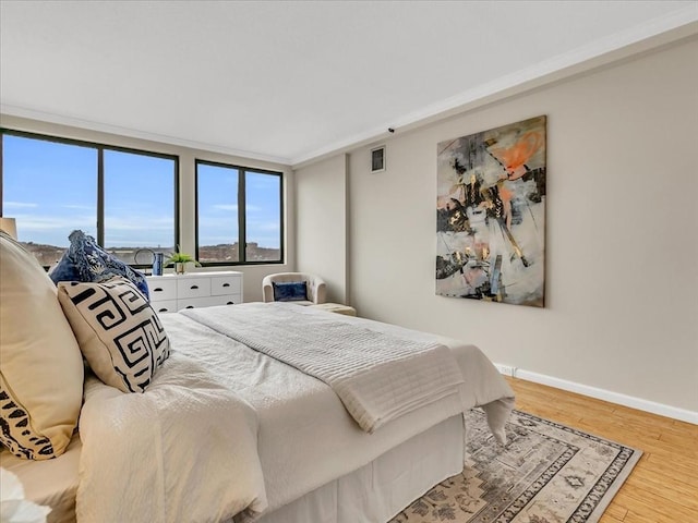 bedroom with baseboards, visible vents, and wood finished floors