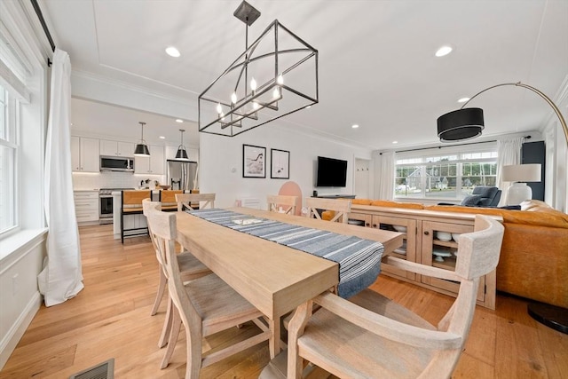 dining room with crown molding, light wood-style flooring, and visible vents