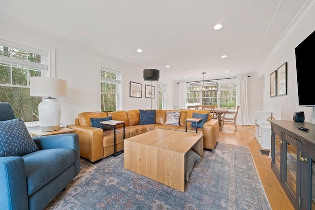 living room with crown molding, recessed lighting, light wood-style flooring, and a notable chandelier