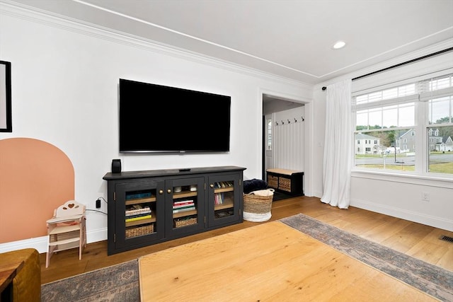 living area with recessed lighting, baseboards, wood finished floors, visible vents, and ornamental molding