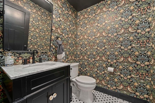 bathroom featuring vanity, toilet, and wallpapered walls