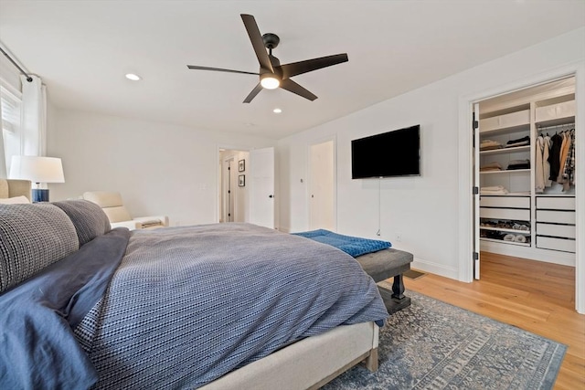 bedroom with recessed lighting, baseboards, a walk in closet, and wood finished floors