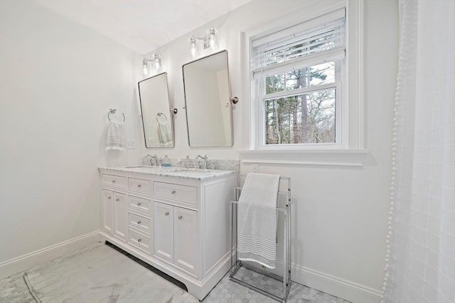 bathroom featuring a sink, baseboards, and double vanity