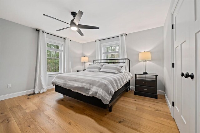 bedroom featuring baseboards, multiple windows, and light wood-style floors