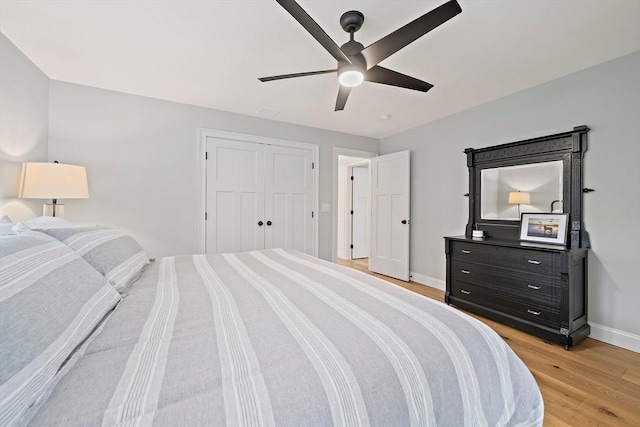 bedroom featuring light wood-style floors, baseboards, ceiling fan, and a closet