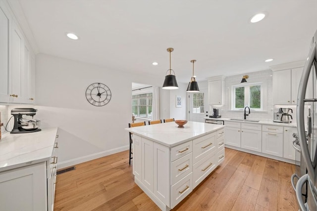 kitchen with decorative backsplash, light wood-type flooring, recessed lighting, white cabinetry, and a sink