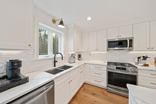 kitchen with a sink, white cabinetry, backsplash, and stainless steel appliances