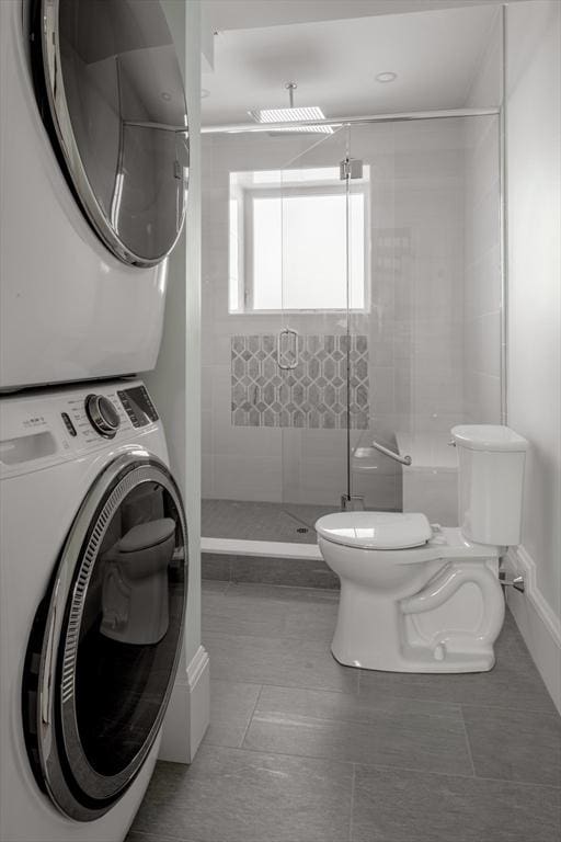 bathroom with stacked washer / dryer, walk in shower, tile patterned flooring, and toilet