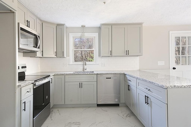 kitchen with sink, kitchen peninsula, pendant lighting, a textured ceiling, and appliances with stainless steel finishes