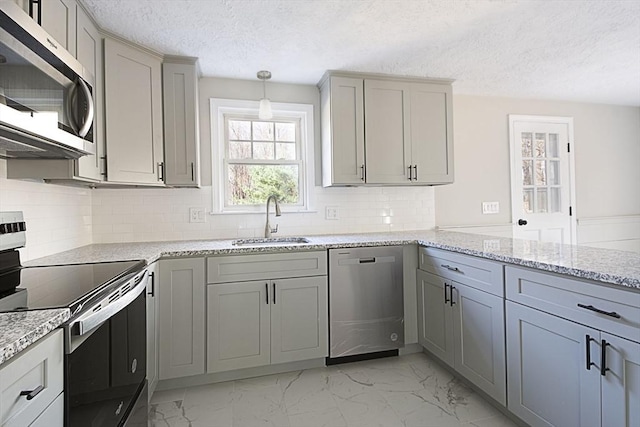 kitchen with decorative backsplash, a textured ceiling, stainless steel appliances, sink, and gray cabinets