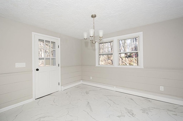 unfurnished dining area featuring a chandelier and a textured ceiling