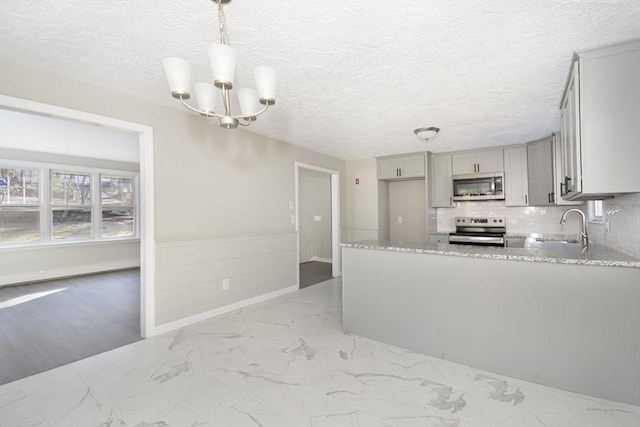 kitchen featuring gray cabinetry, sink, a textured ceiling, appliances with stainless steel finishes, and decorative light fixtures