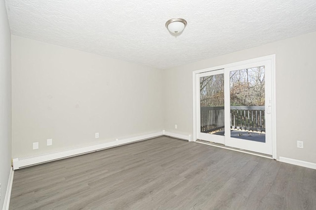 empty room featuring dark hardwood / wood-style flooring, a baseboard radiator, and a textured ceiling