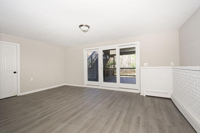 unfurnished room with dark wood-type flooring and brick wall