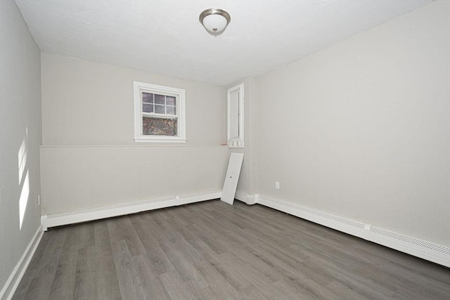 unfurnished room featuring hardwood / wood-style flooring and a baseboard heating unit