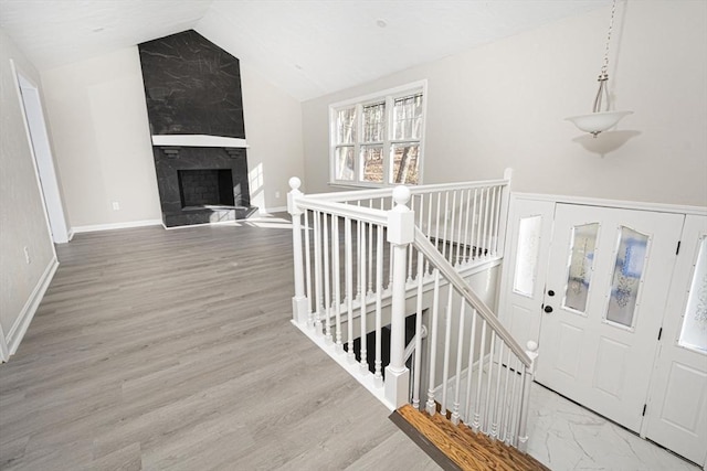 stairway featuring hardwood / wood-style floors, a fireplace, and vaulted ceiling