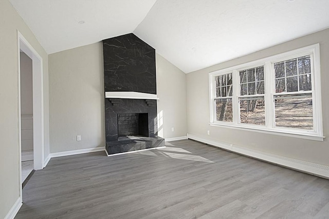 unfurnished living room featuring hardwood / wood-style flooring, baseboard heating, lofted ceiling, and a tiled fireplace