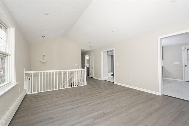 empty room featuring vaulted ceiling, dark hardwood / wood-style flooring, and a baseboard radiator