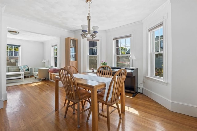 dining room featuring baseboards, a chandelier, ornamental molding, and wood finished floors