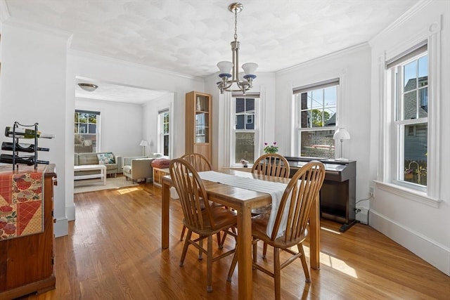 dining area featuring an inviting chandelier, ornamental molding, and wood finished floors