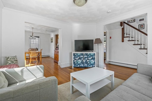 living area featuring an inviting chandelier, baseboard heating, stairs, wood finished floors, and ornamental molding