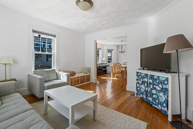 living area featuring crown molding, baseboards, an inviting chandelier, and wood finished floors