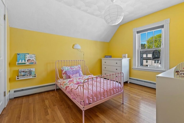 bedroom with wood finished floors, baseboard heating, and vaulted ceiling