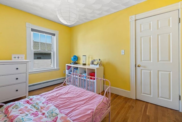 bedroom featuring baseboards, baseboard heating, and wood finished floors